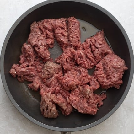 Beef in a skillet before cooking.