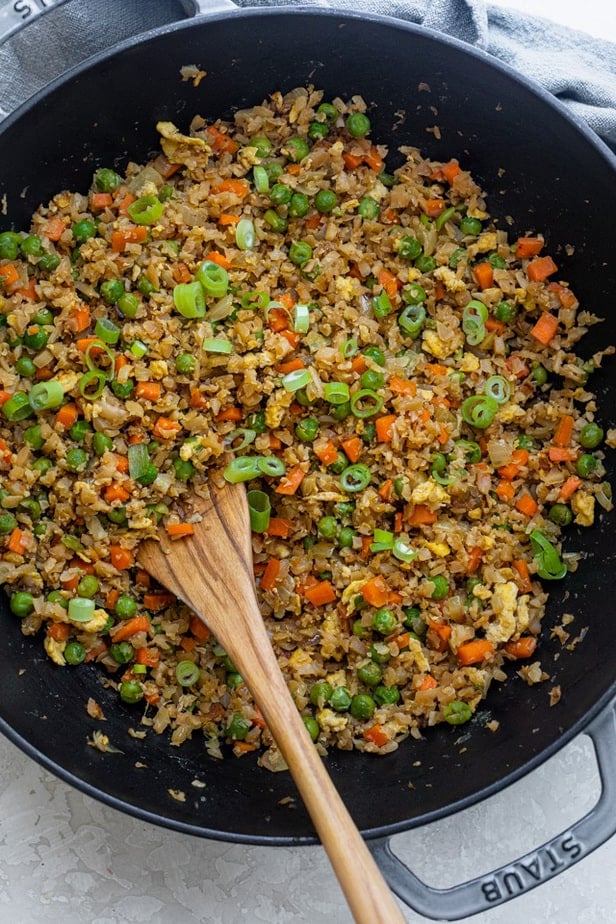 Cauliflower fried rice in a skillet with a wooden spoon