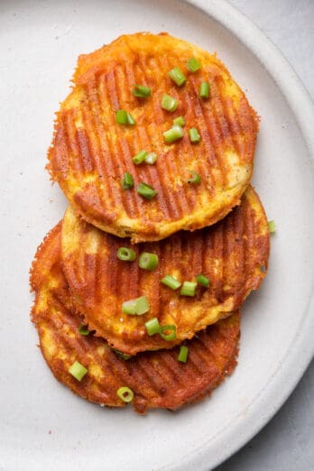 3 stacked chaffles on top of each other on a plate garnished with green onions