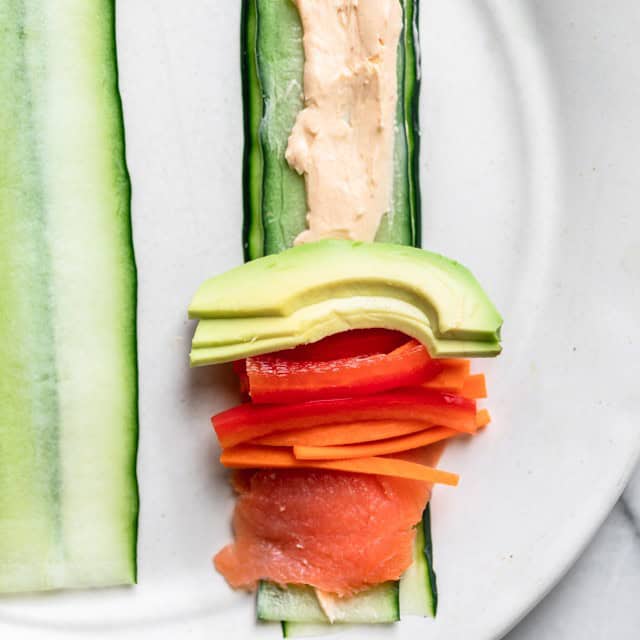One piece of cucumber laid flat with sauce smeared across its length and fillings stacked.