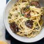 Creamy garlic mushroom pasta in a bowl with parmesan cheese next to it