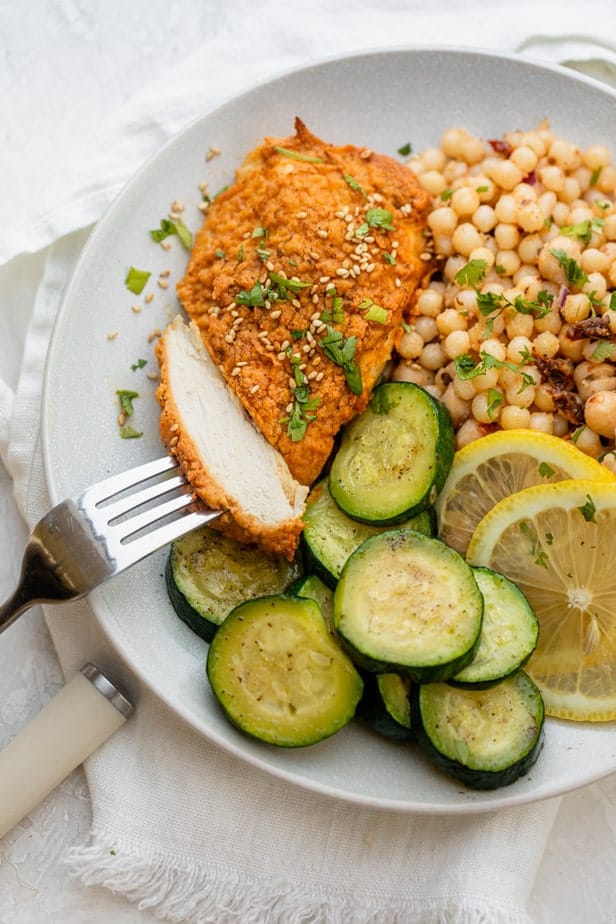 Hummus crusted chicken being cut with a fork