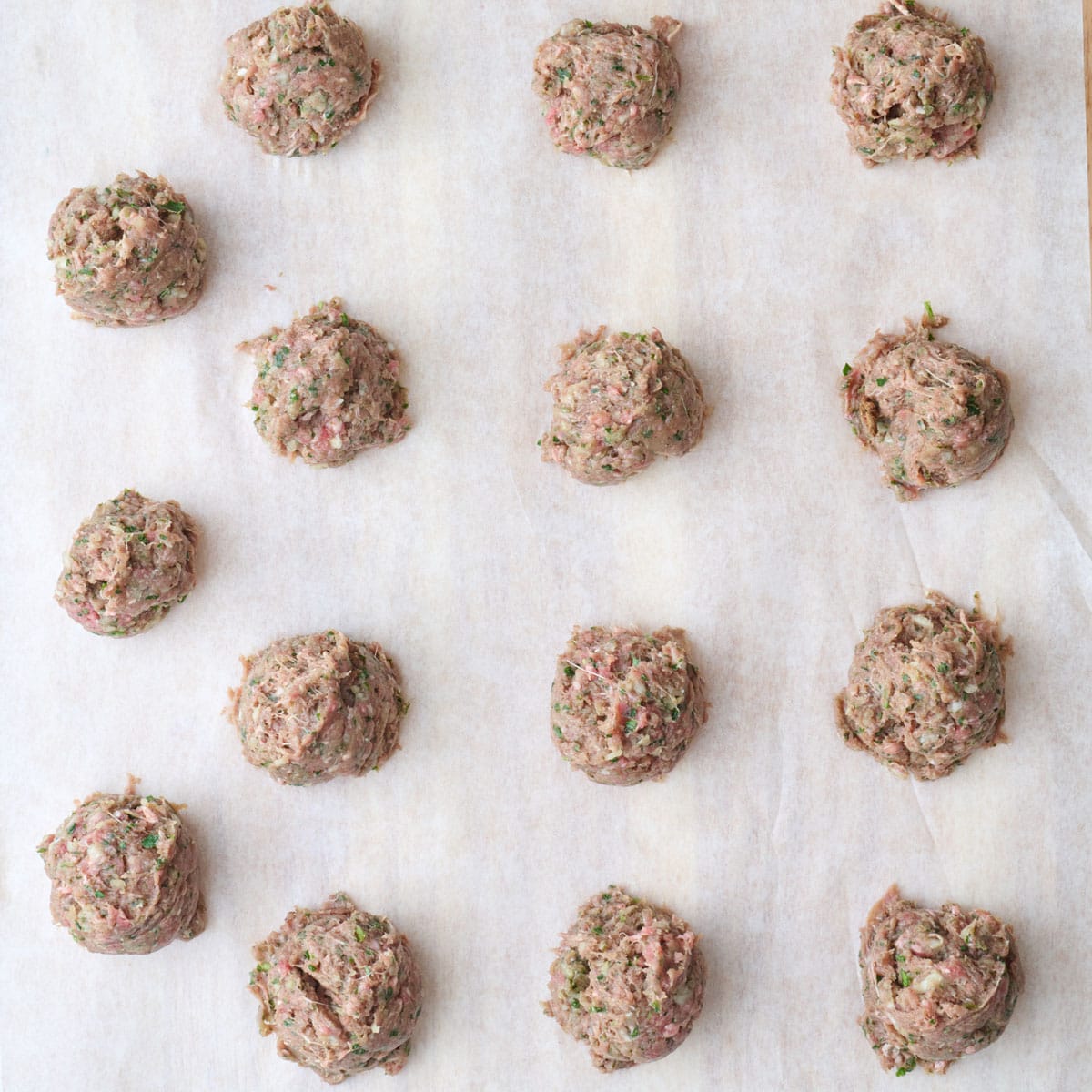 Kafta balls on a board lined with parchment.