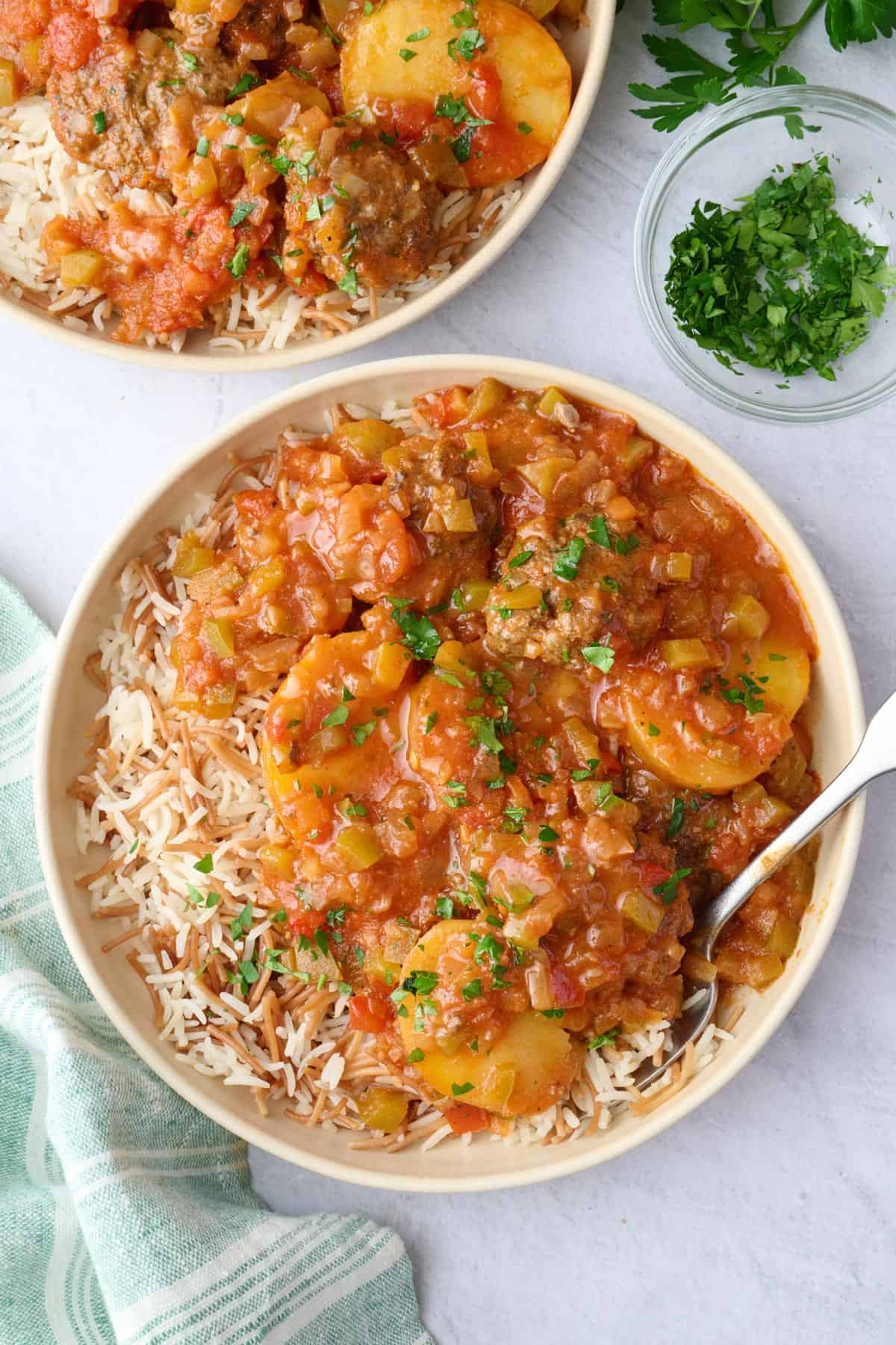 Two shallow bowls with Lebanese rice and kafta potato stew served on top.