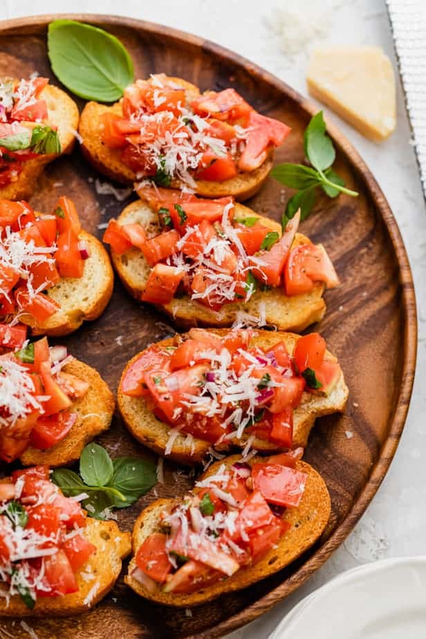 Tomato Basil Bruschetta served on a wooden plate and topped with cheese