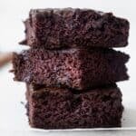 Three zucchini brownie squares stacked on top of each other.