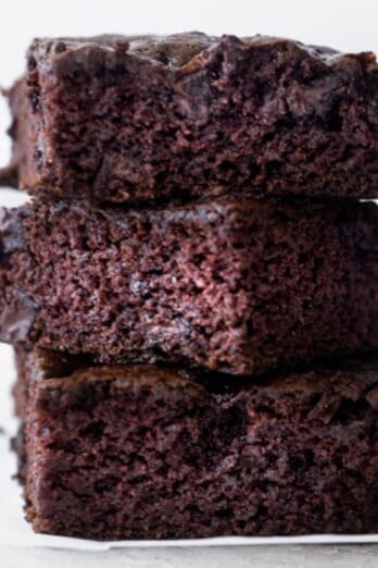 Three zucchini brownie squares stacked on top of each other.