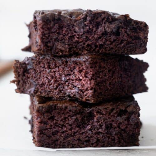 Three zucchini brownie squares stacked on top of each other.