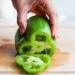 hand holding a green bell peppers