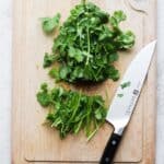 cilantro with ends cut off on a wooden chopping board