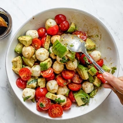 Mixing the salad together with a spoon.