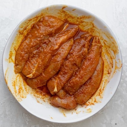 Chicken in a bowl after mixing with seasonings.