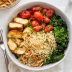 Chicken and quinoa bowl in a large serving bowl with toppings.