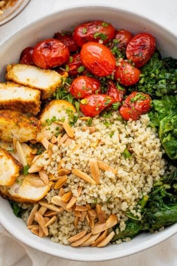 Chicken and quinoa bowl in a large serving bowl with toppings.
