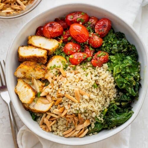 Chicken and quinoa bowl in a large serving bowl with toppings.