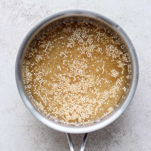 Quinoa in a pot with liquids added.