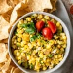 Close up shot of bowl of corn salsa with chips around the bowl