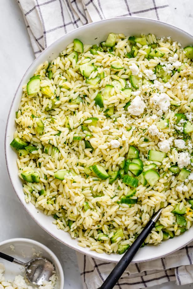 Cucumber lemon orzo salad topped with feta cheese with small bowl of feta on the side