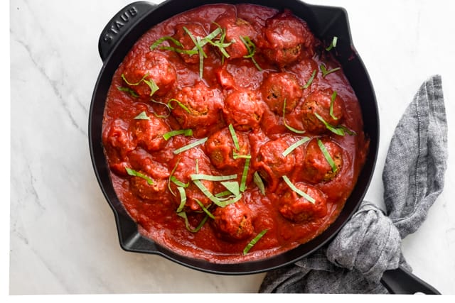 Finished meatless meatballs in a skillet with marinara sauce topped with basil