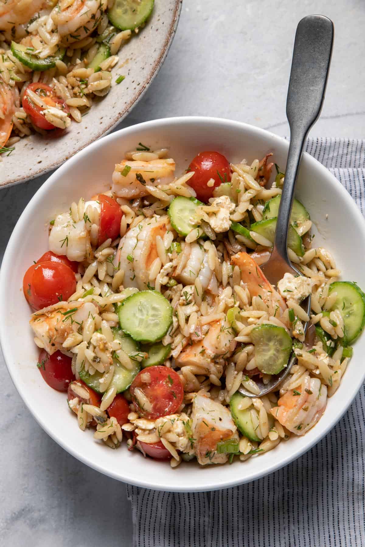 Large bowl of shrimp orzo salad with spoon inside