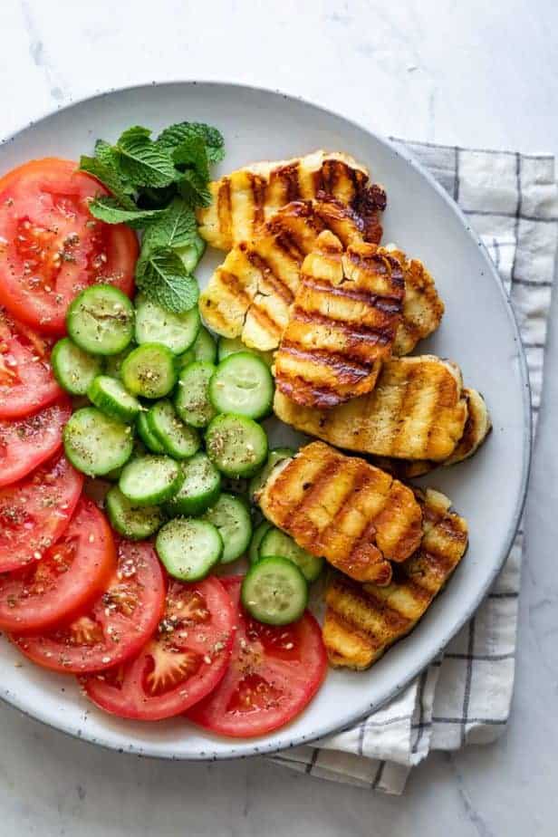 Halloumi cheese on circular platter with tomatoes, cucumbers and mint
