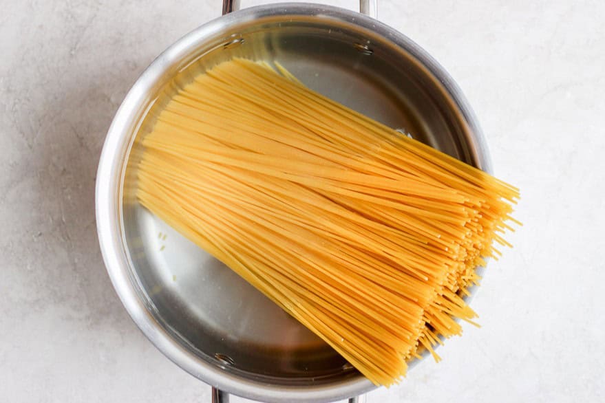 Uncooked spaghetti in a pot of water.