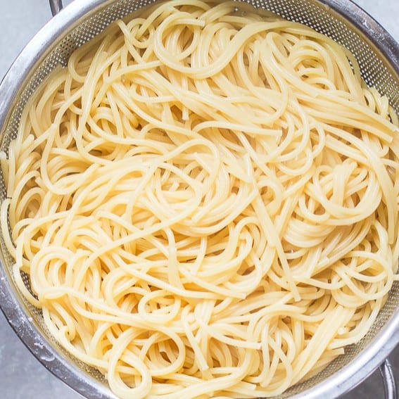 Cooked spaghetti in a strainer.