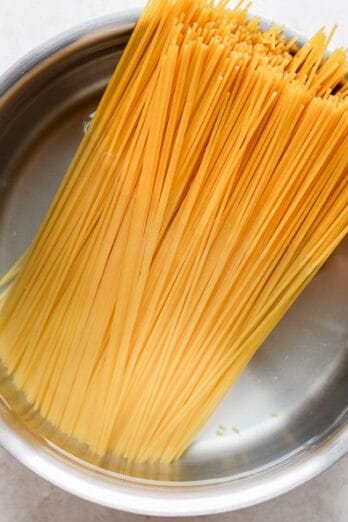 Uncooked spaghetti in a pot of water.