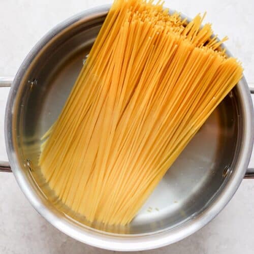 Uncooked spaghetti in a pot of water.