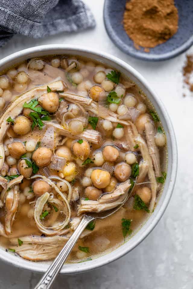 Spoon inside bowl of chicken moghrabieh