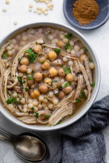 Chicken moghrabieh in a large bowl with chickpeas on top