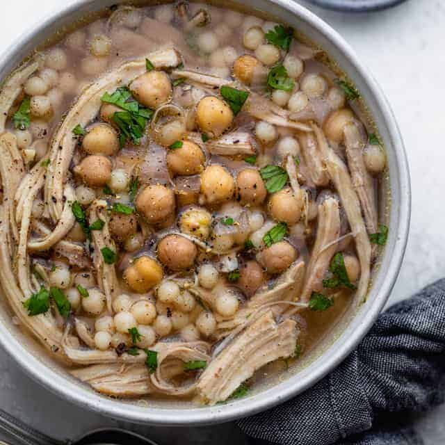 Chicken moghrabieh in a large bowl with chickpeas on top