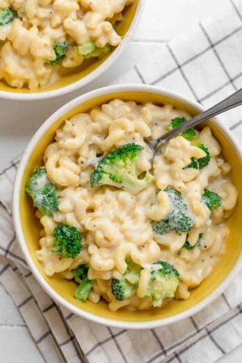 Large bowl of broccoli mac and cheese with spoon inside and second bowl nearby