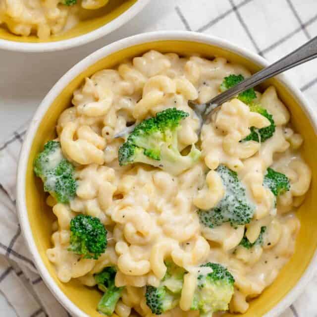 Large bowl of broccoli mac and cheese with spoon inside and second bowl nearby
