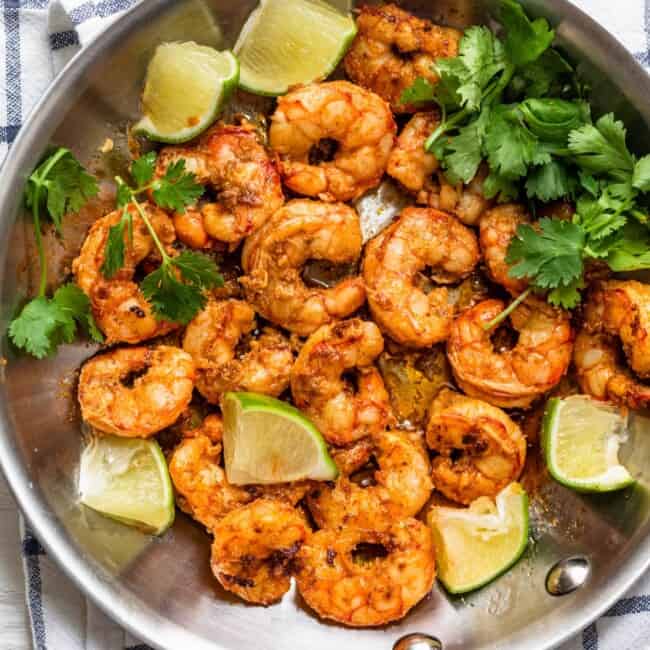 Chili lime shrimp in a pan with garnish and lime.