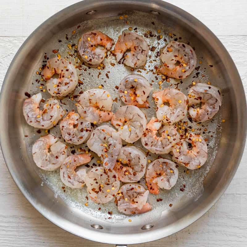 Seasoned shrimp in pan on stove.