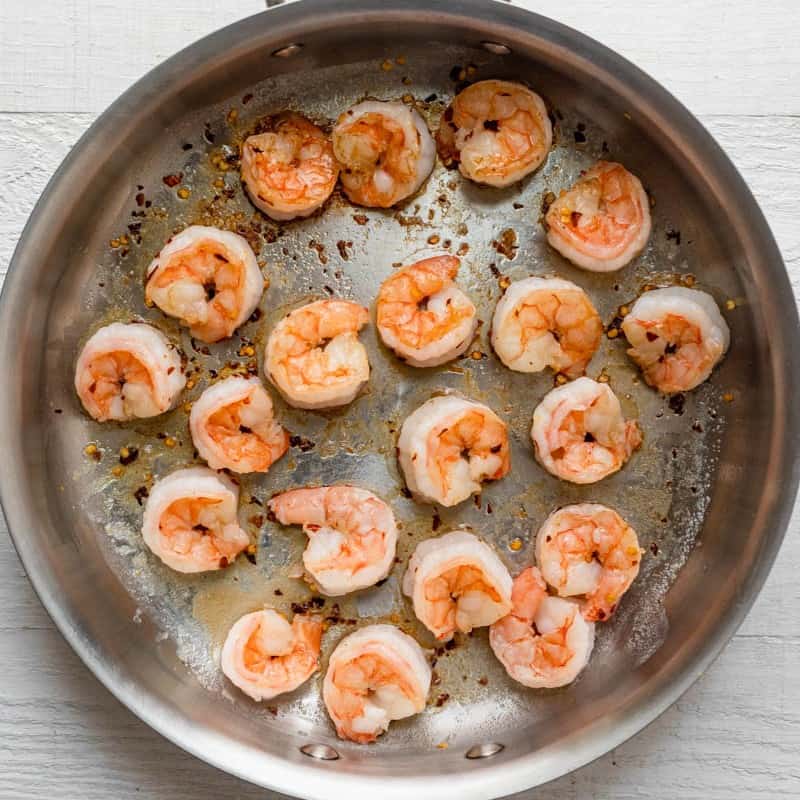 Shrimp in pan on the stove after flipping halfway through cooking.