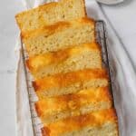 Lemon bread recipe sliced on a cooling rack with lemon wedges near by