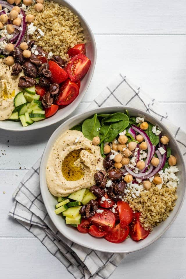 Two large Mediterranean hummus bowls filled with veggies and hummus