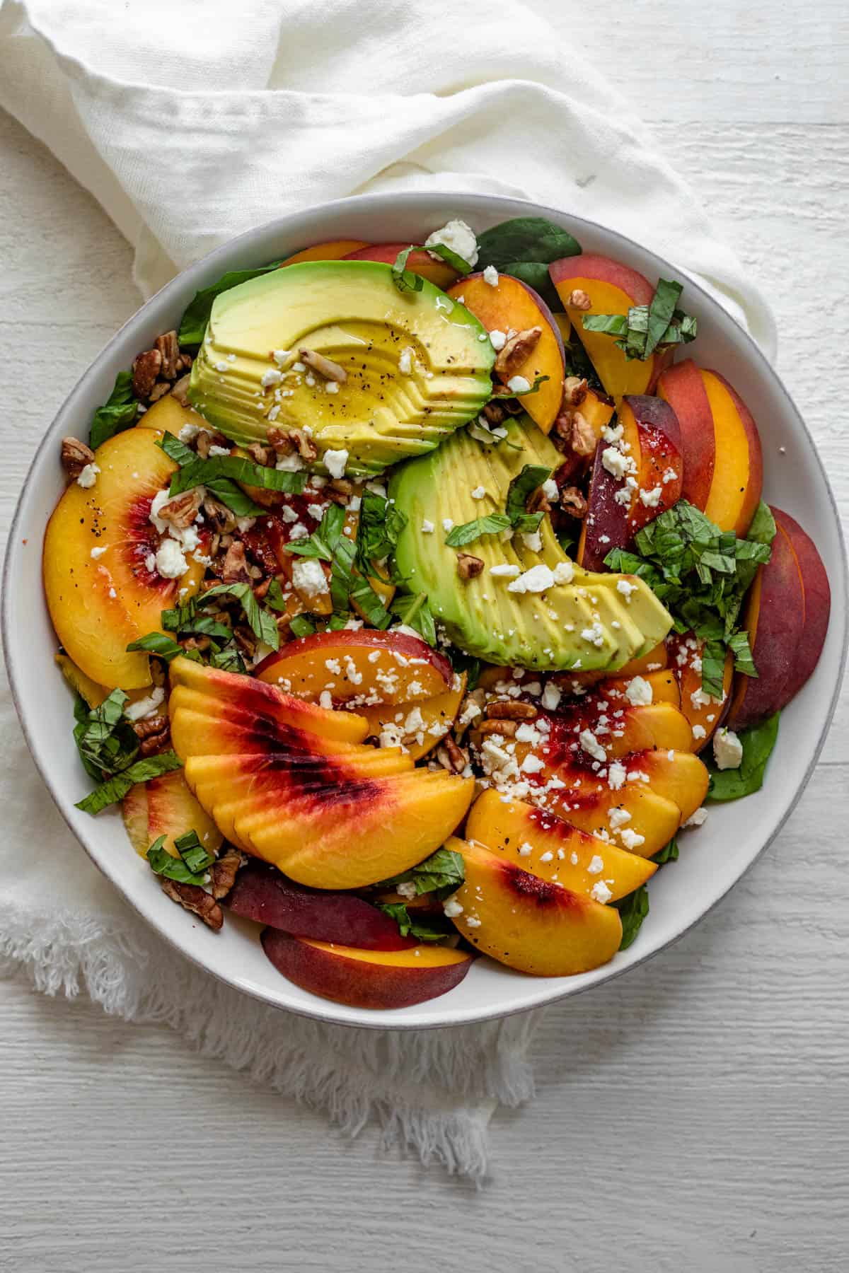 Large bowl of peach salad with sliced avocados