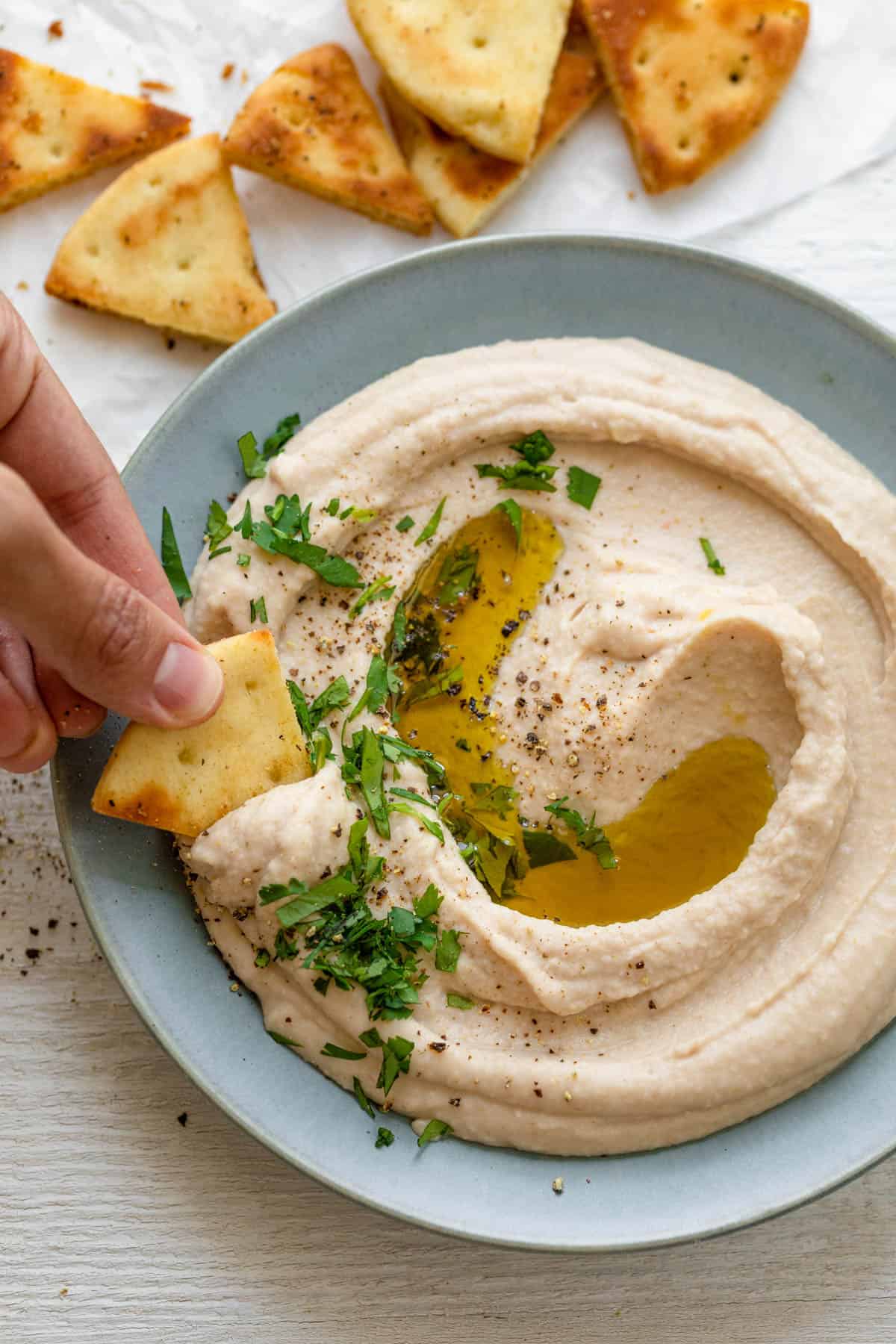 White bean hummus with pita chip dipping into it
