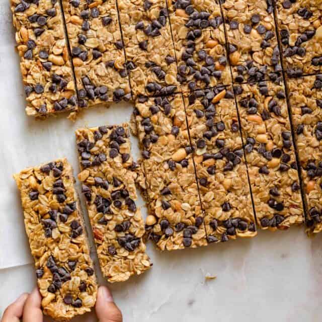 Chocolate Peanut Butter Granola Bars sliced with hand grabbing one