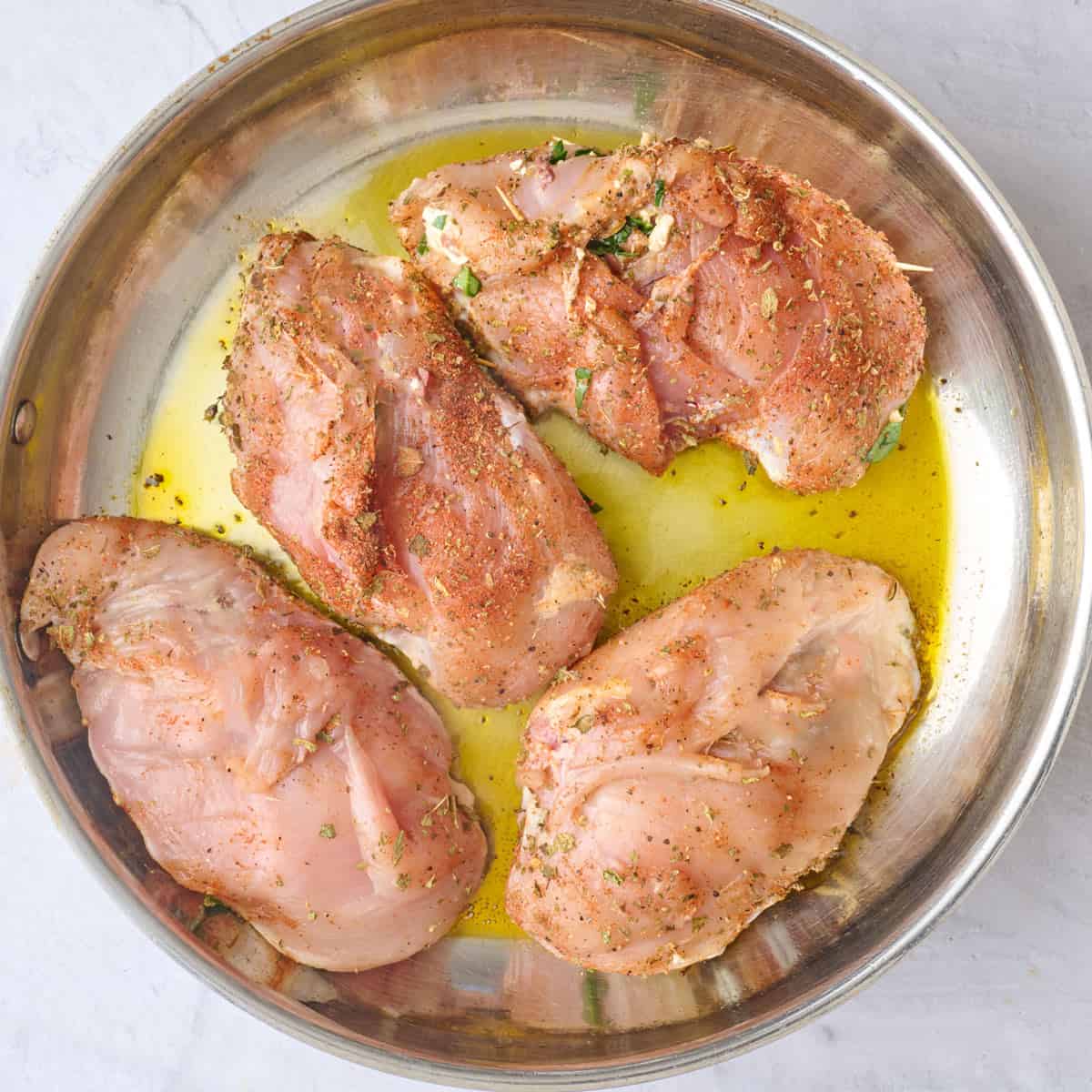 Chicken after closing with toothpicks in an oiled skillet before cooking.