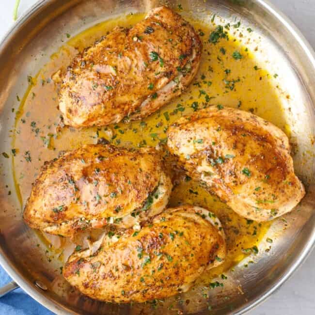 Stuffed chicken in the skillet garnished with chopped parsley.
