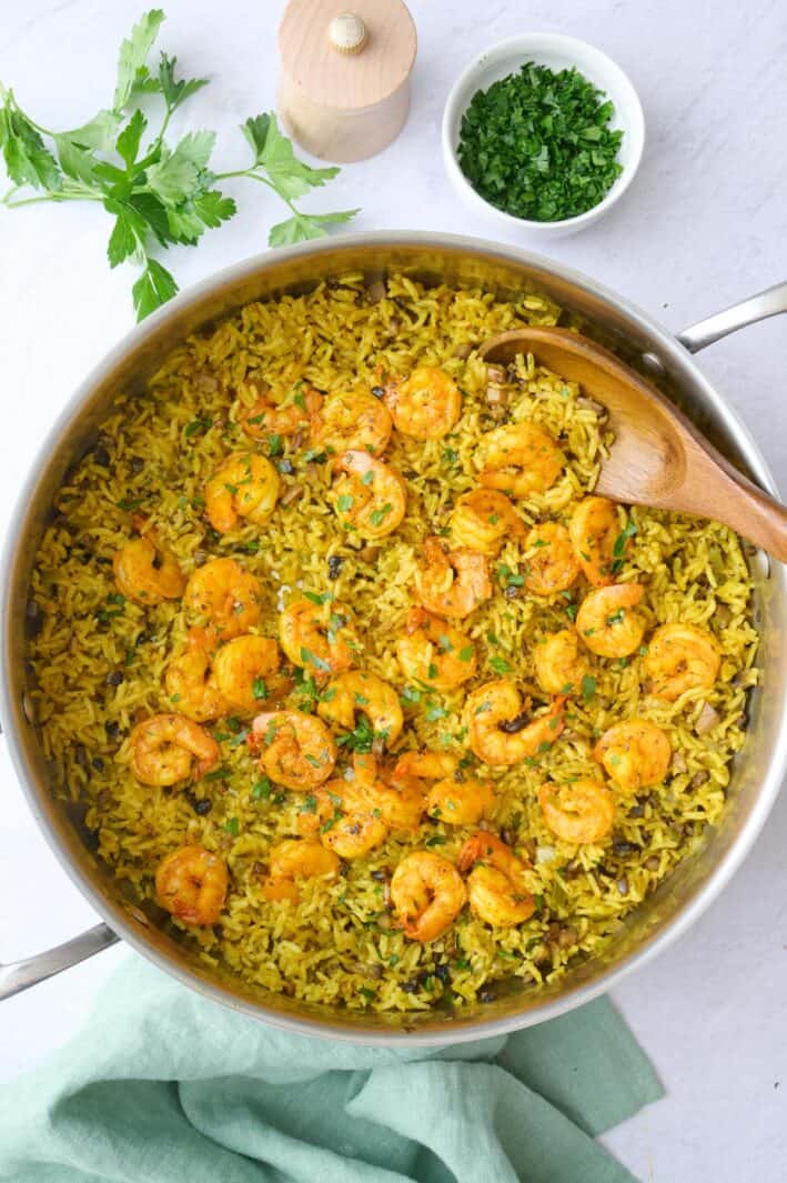 Shrimp and rice in the pot after fluffing rice, garnished with chopped parsley.