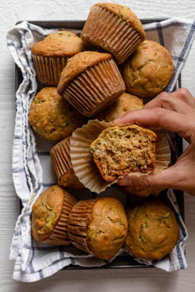 Large dish of muffins with hand holding half a muffin cut in half
