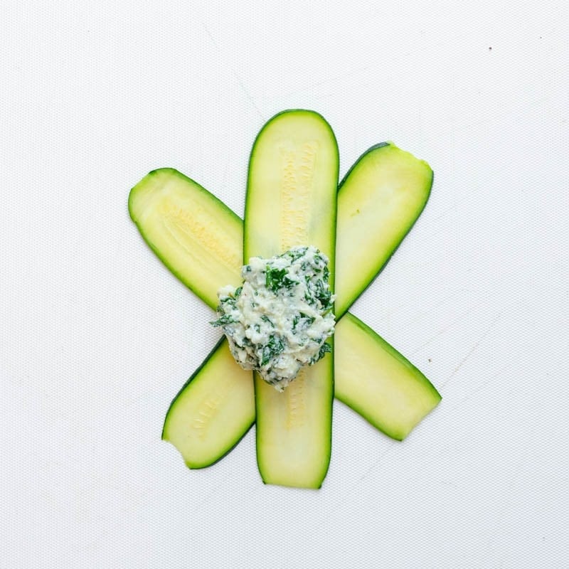 Three slices of zucchini laid down in an asterisk shape with a dollop of the zucchini ravioli filling in the middle.