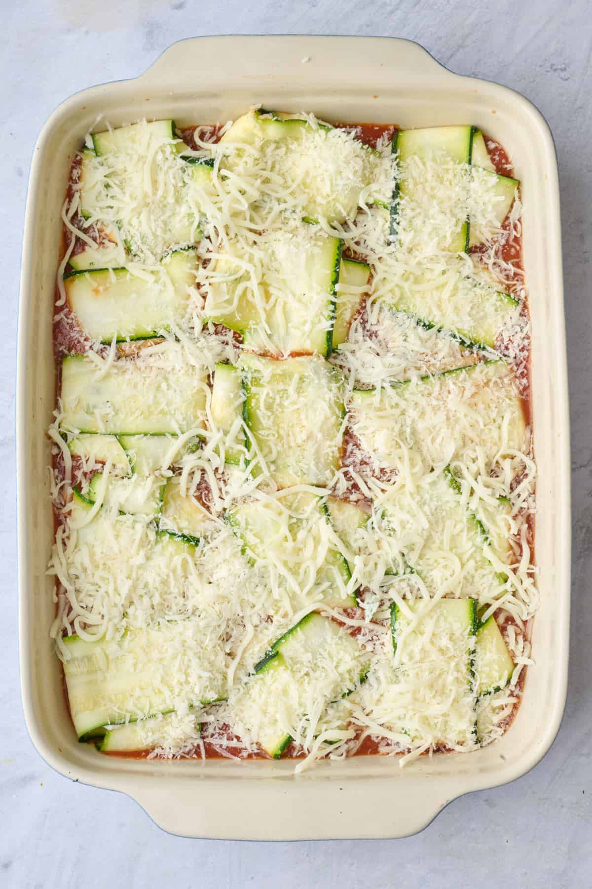 Marinara sauce in the bottom of a baking dish with raviolis placed seam side down, mozzarella and parmesan cheese added before baking.