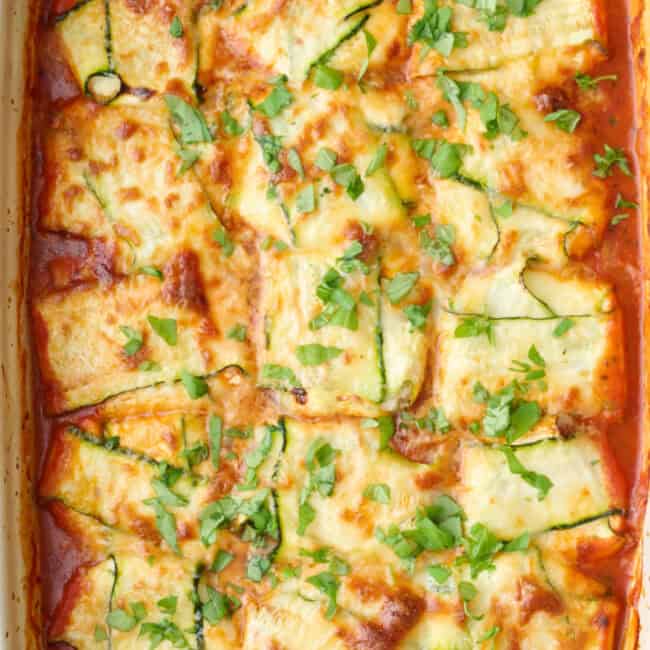 Zucchini ravioli in the baking dish garnished with basil.