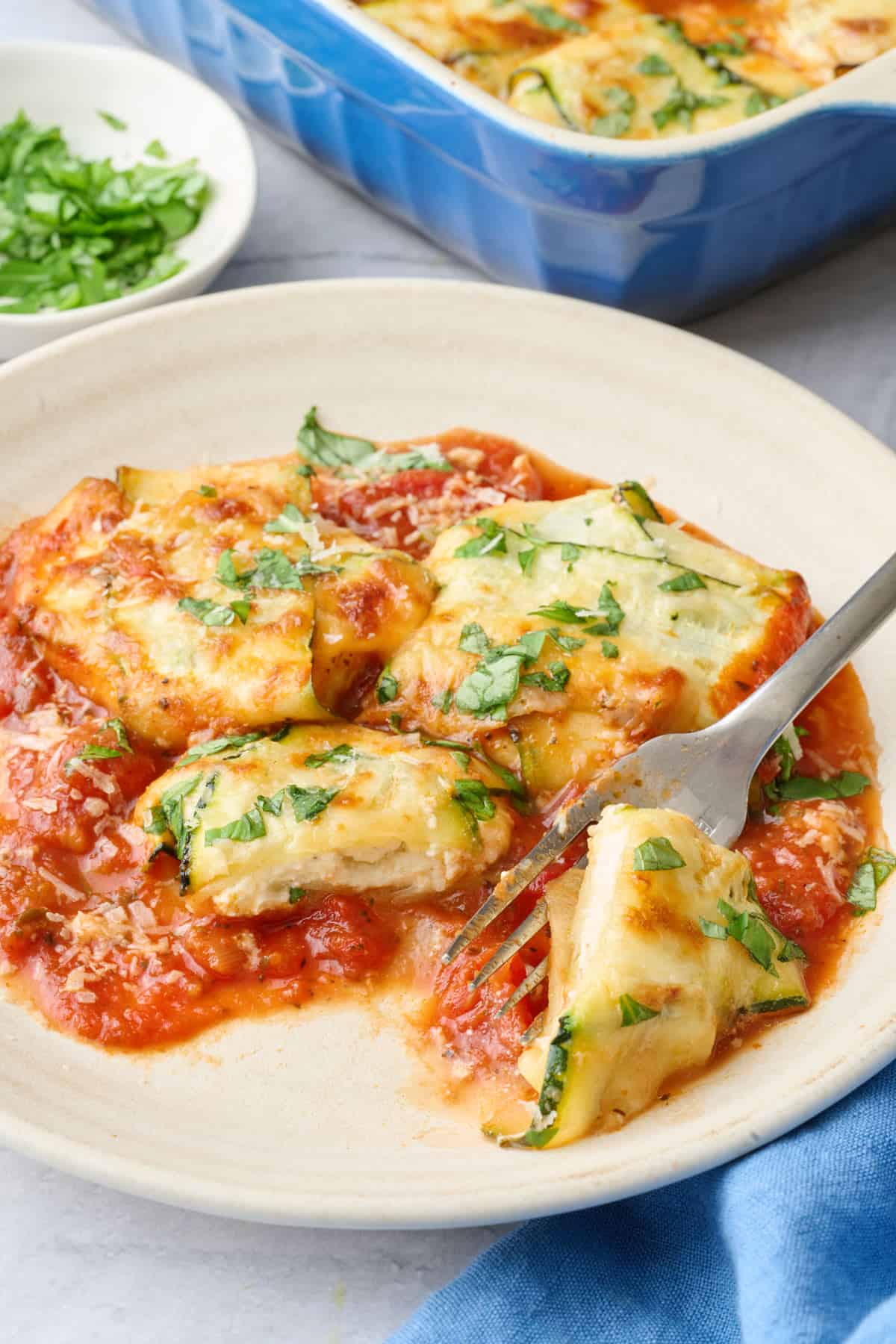 3 raviolis on a plate with sauce and baking dish nearby.